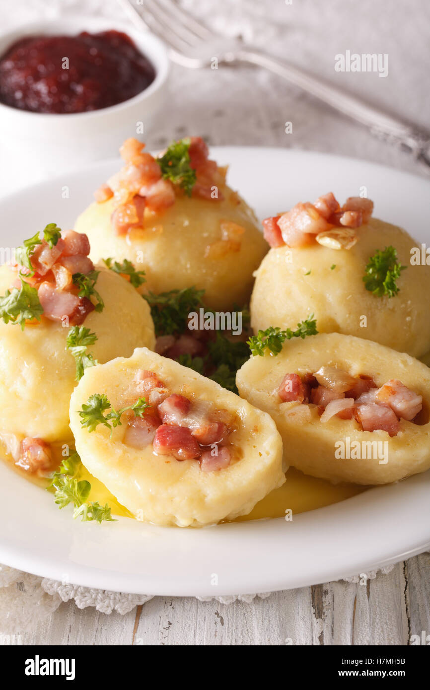 Potato dumplings stuffed with ham, bacon and onion close-up on a plate and lingonberry sauce. Vertical Stock Photo