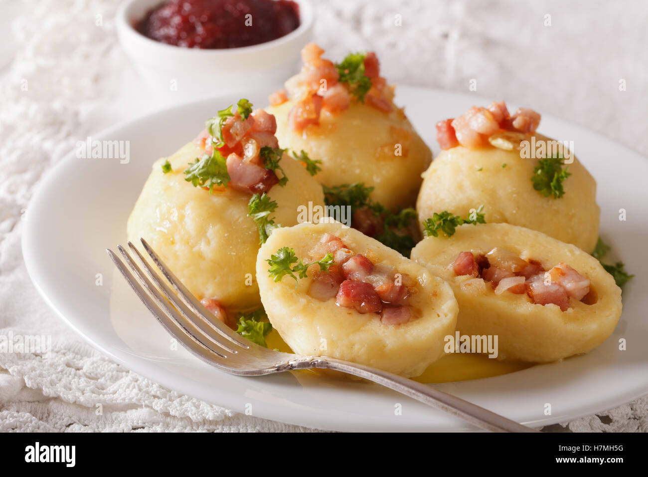 Potato dumplings stuffed with ham, bacon and onion close-up on a plate and lingonberry sauce. horizontal Stock Photo