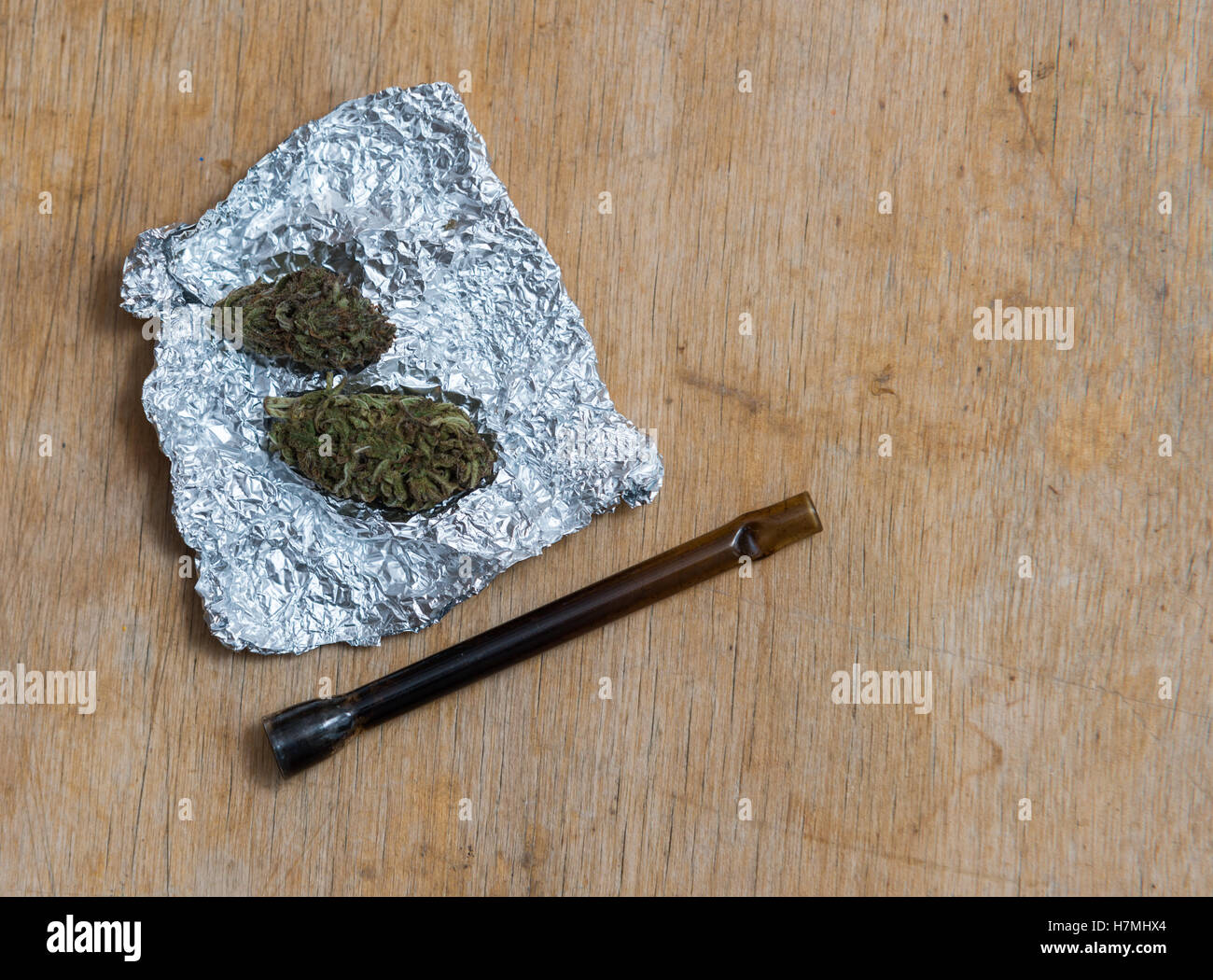 Marijuana in tin foil with pipe on wooden table Stock Photo Alamy