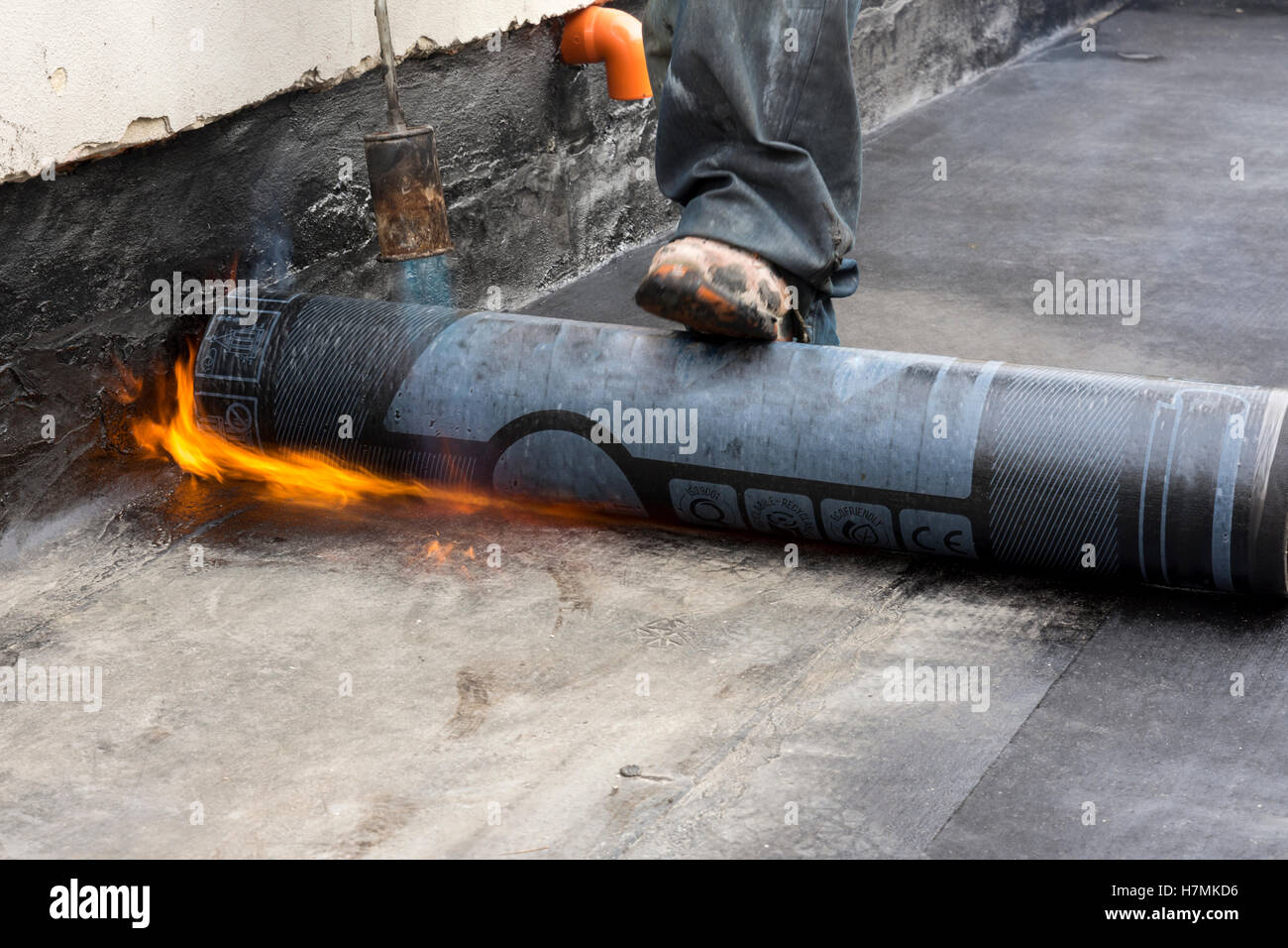 worker while burning the waterproof membrane on a roof Stock Photo