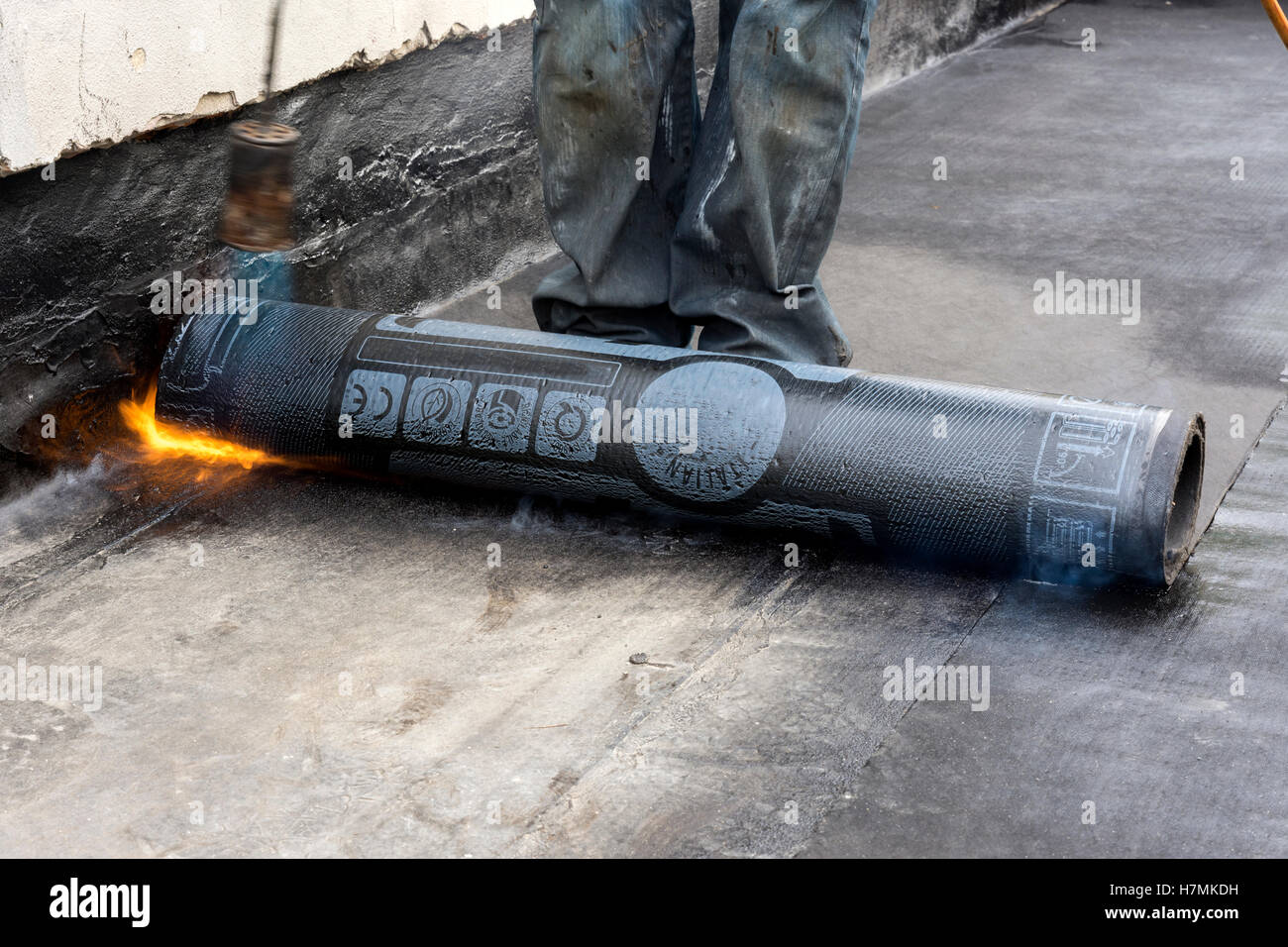 worker while burning the waterproof membrane on a roof Stock Photo