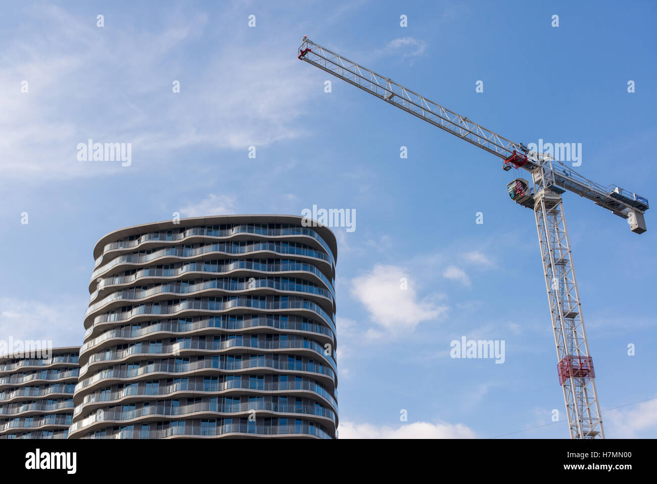 Big construction crane with two high-rise modern apartment buildings next to it Stock Photo