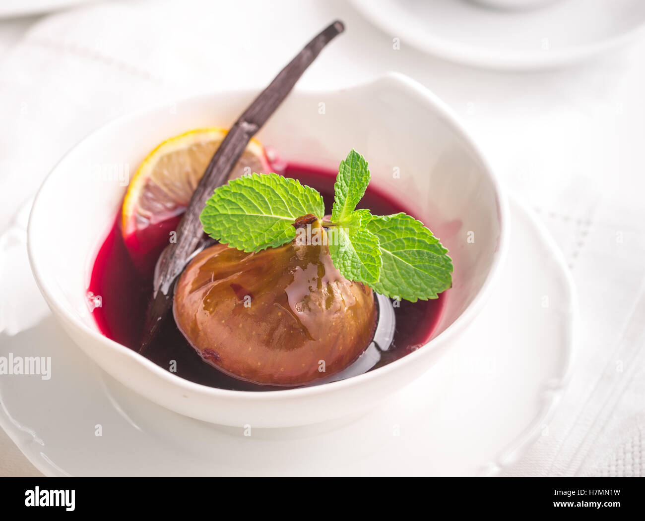 Poached fig in red wine with mint and vanilla in light colors Stock