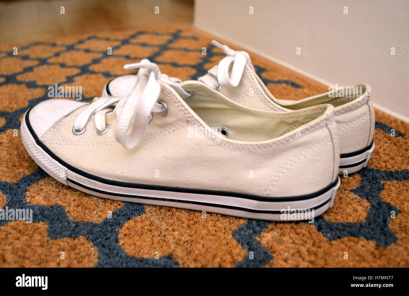Closeup of a pair of white colured Converse All star trainers on a doormat. Stock Photo