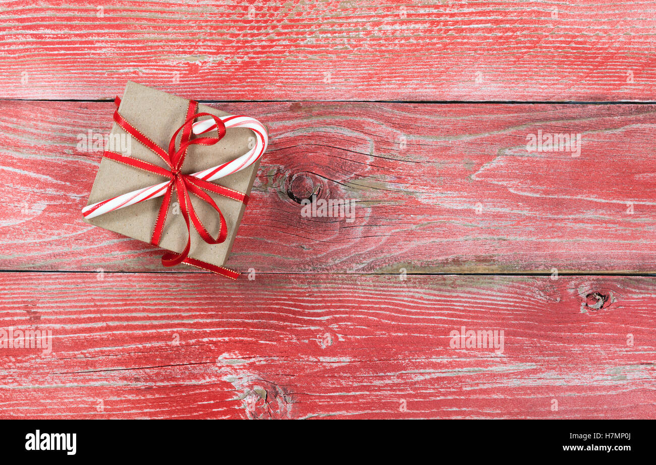 Gift box and candy cane on rustic red wooden boards. Overhead view with copy space Stock Photo