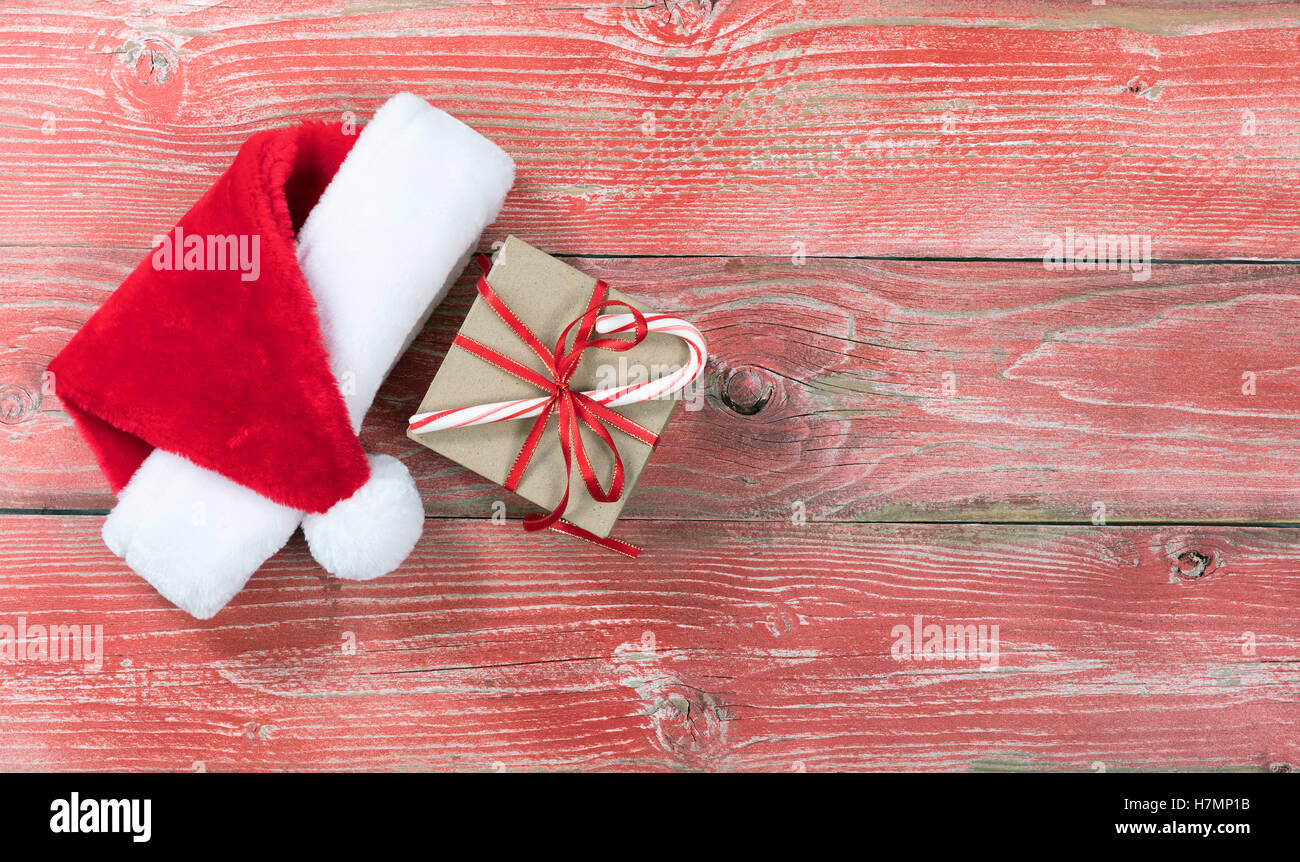 Gift box and Santa cap on rustic red wooden boards. Overhead view with copy space. Stock Photo