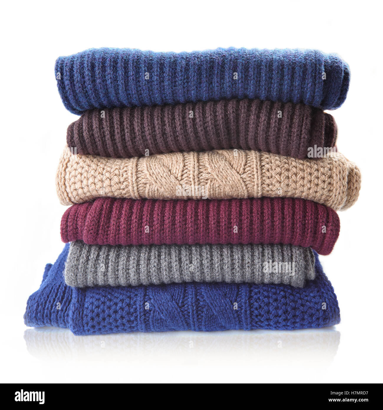 Pile of knitted winter clothes isolated on white, sweaters, knitwear