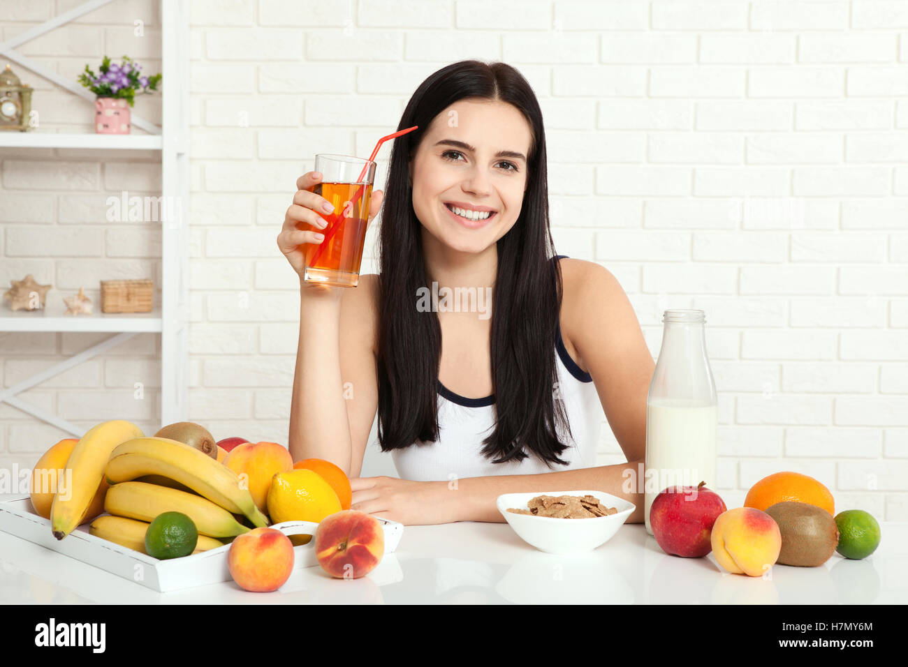 Beautiful women exists with pure skin on her face sitting at a table and eat breakfast. Asian woman eating healthy food at breakfast. Fruit, cereal and milk. Stock Photo
