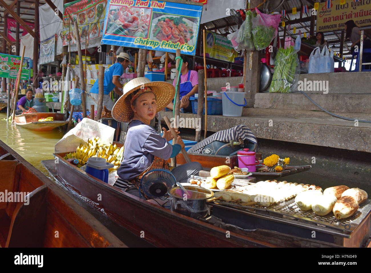 A floating food vendor paddles her canoe selling cooked fruit at
