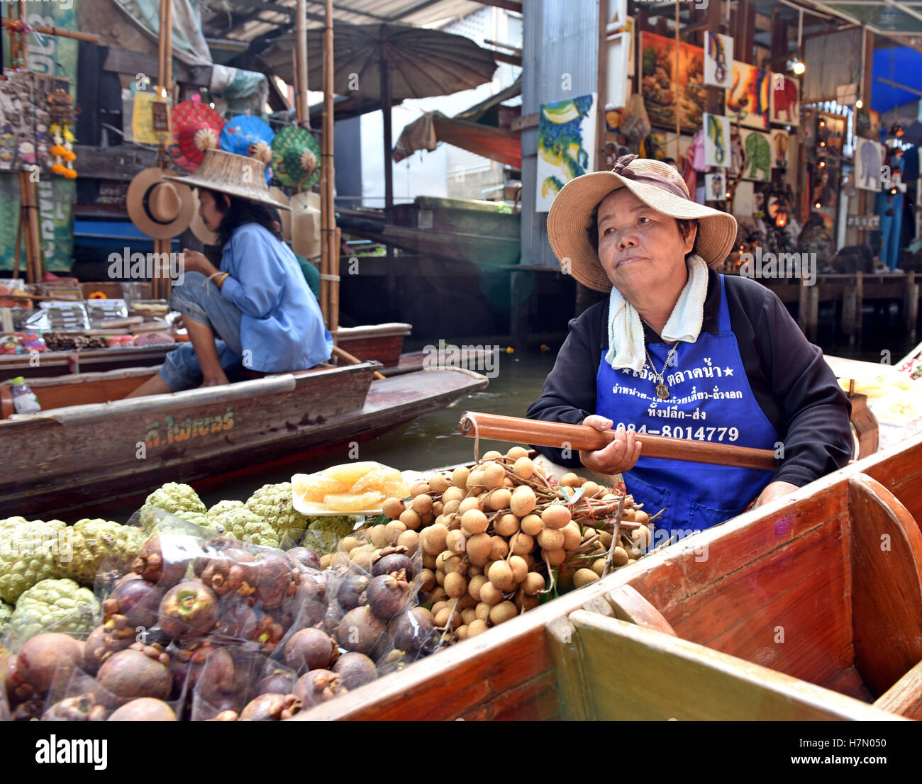 A floating food vendor paddles her canoe selling fresh fruit at Damnoen
