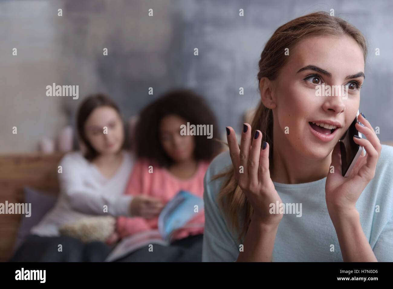 Surprised young girl talking on the phone at home Stock Photo