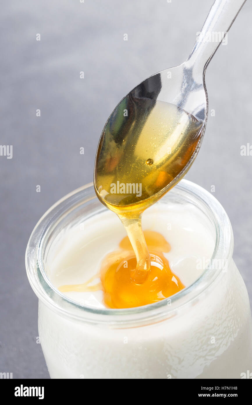 Yogurt and pouring honey on white background Stock Photo