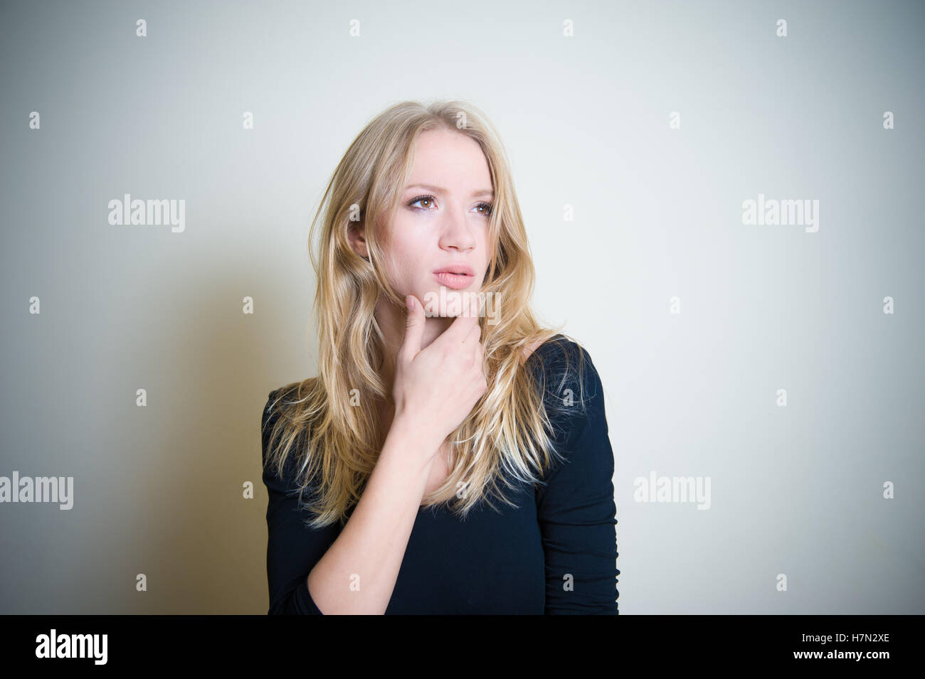 Young blond woman thoughtful looking up, portrait with copy space on side Stock Photo