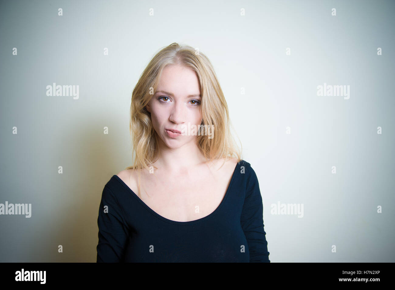 Young blond woman, smirking with little grimace and looking at camera copy space Stock Photo