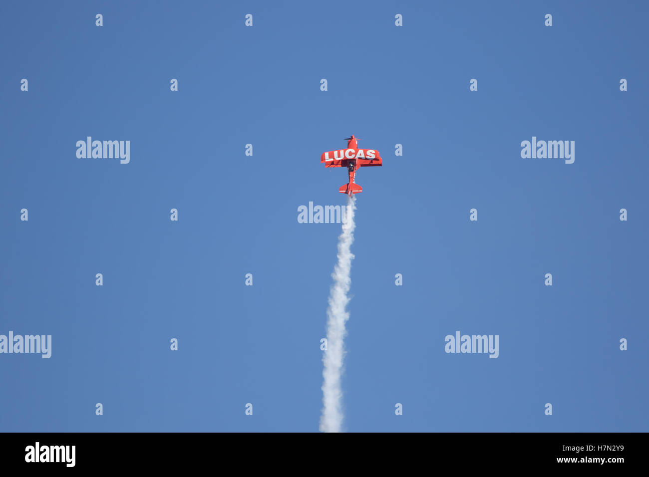 Huntington Beach  air show Lucas oil aerobatics stunt plane soars into a vivid blue sky trailing smoke behind Stock Photo