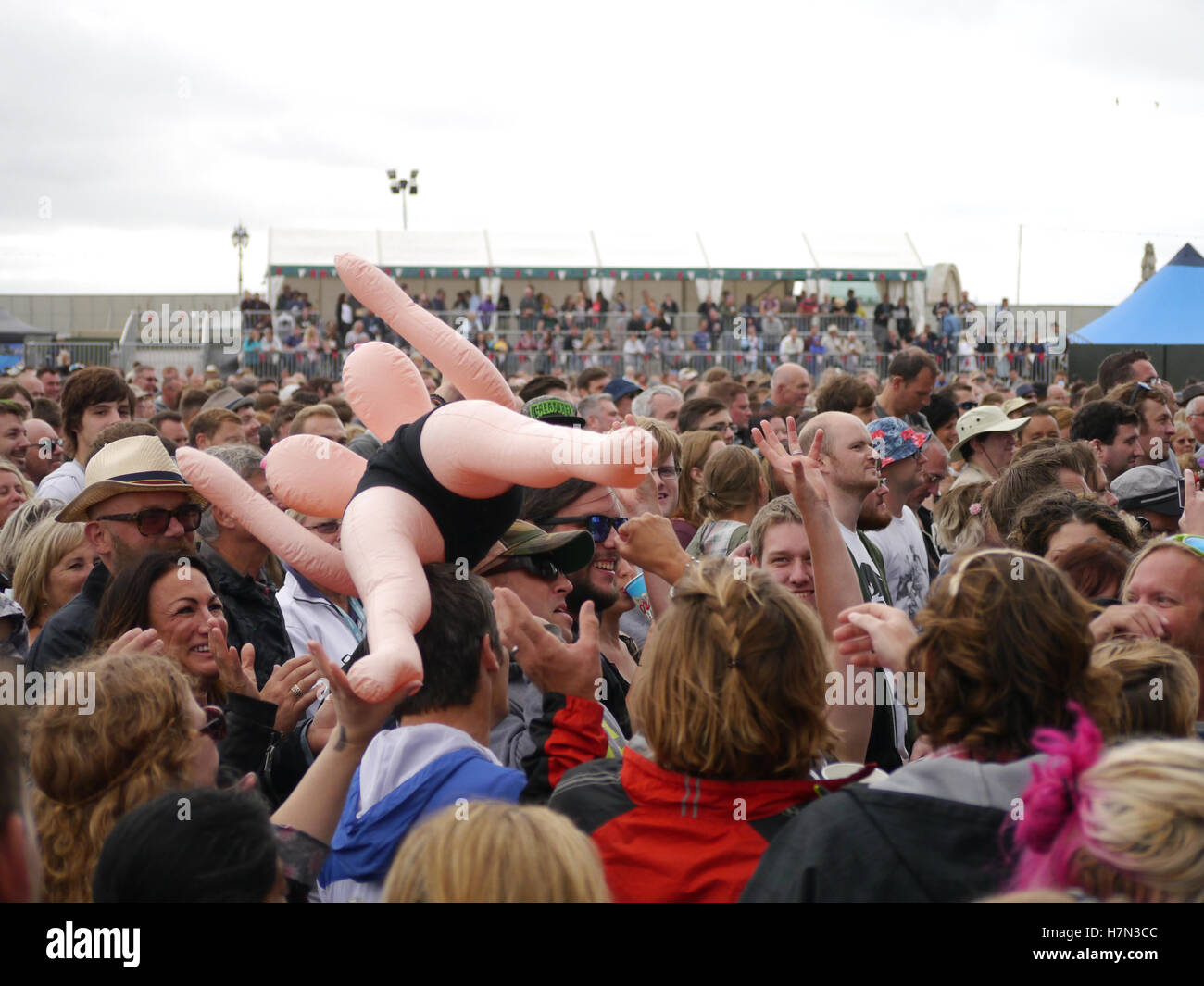 A blow up doll is sent crowd surfing at above a large music festival crowd Stock Photo