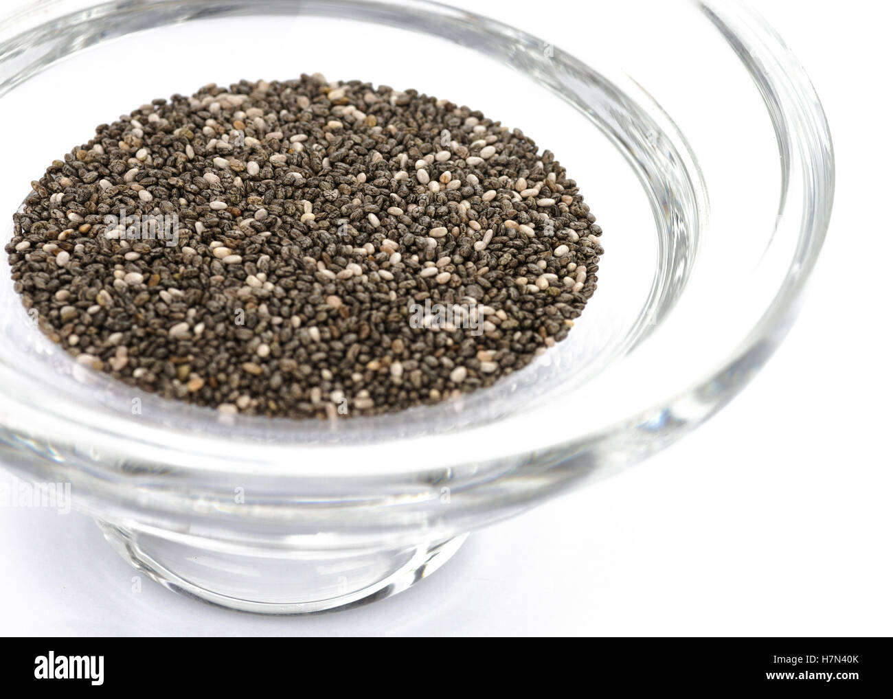 Chia seeds Selective focus in a thick round glass bowl on a bright white background, Stock Photo