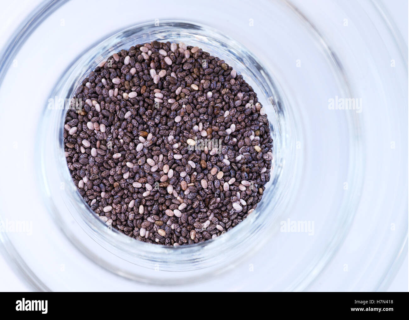 Chia seeds in a lightly tinted glass over head view on a white background , room for text to right side Stock Photo