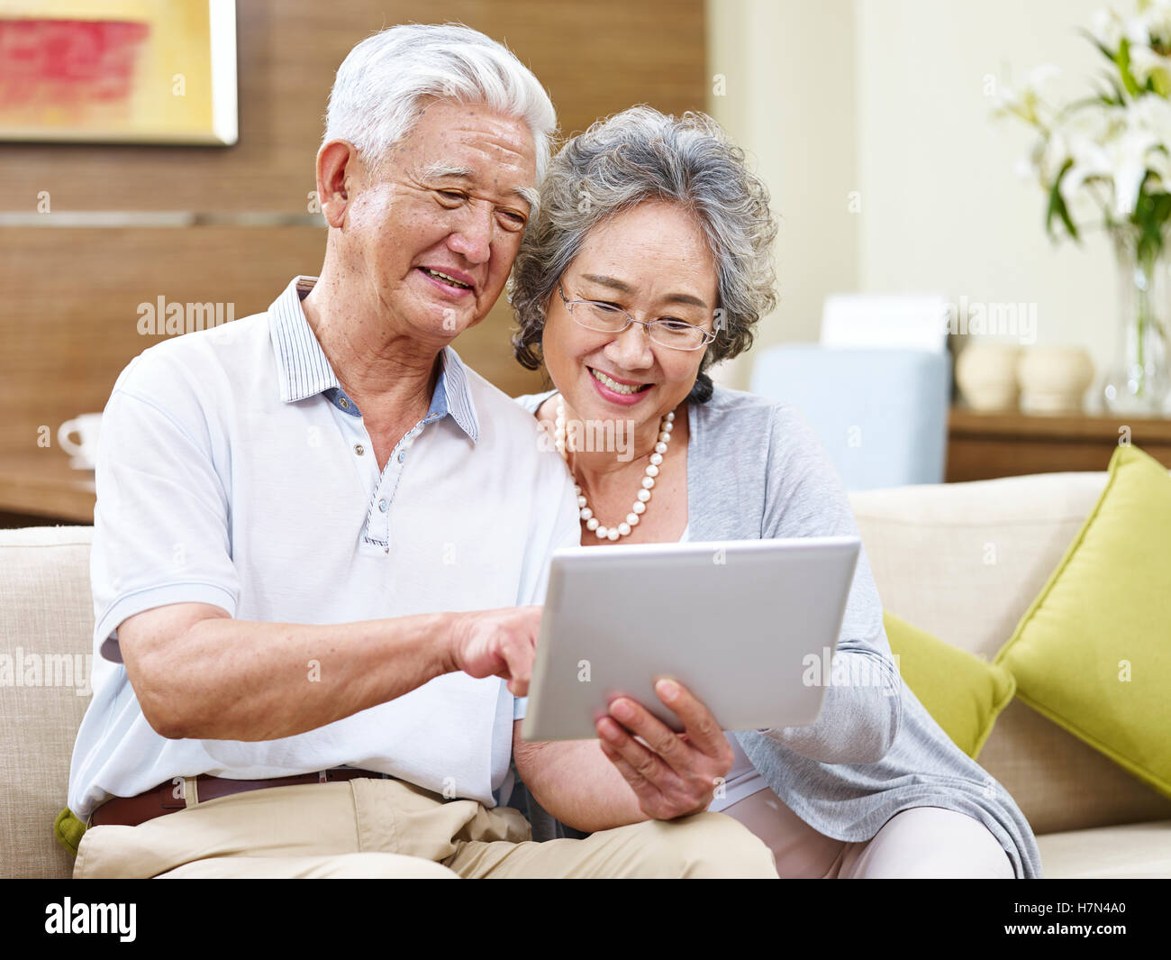 senior asian couple sharing a tablet computer at home Stock Photo