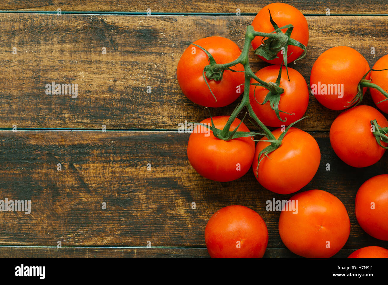 Tomatoes with branch on a wooden rustic background Stock Photo - Alamy