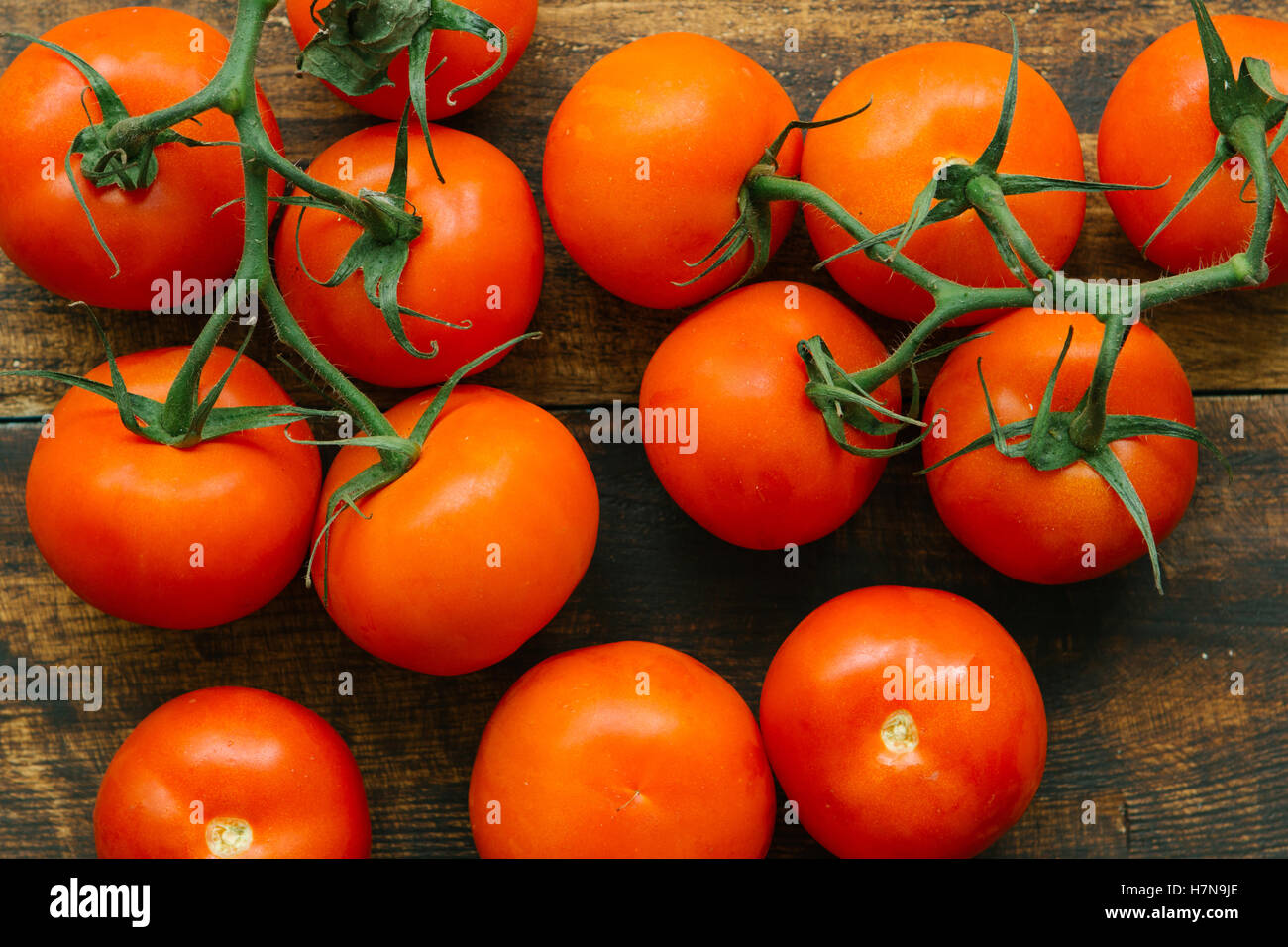 Tomatoes with branch on a wooden rustic background Stock Photo - Alamy