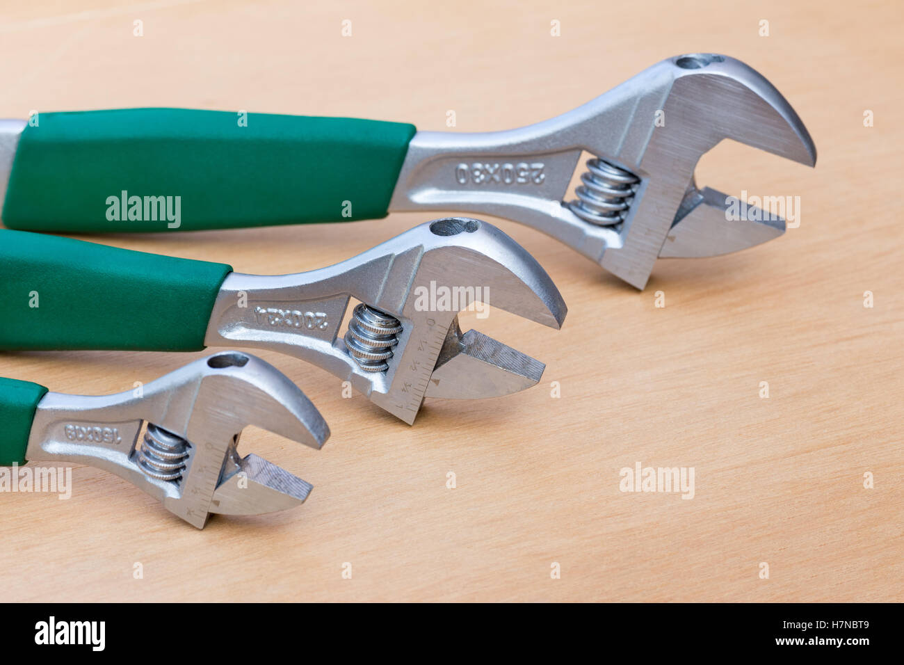 Three adjustable wrenches of different size standing upright on wood Stock Photo
