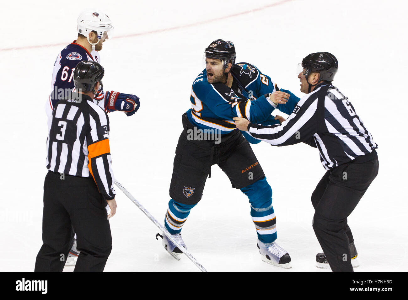 Jan 31, 2012; San Jose, CA, USA; San Jose Sharks defenseman Dan Boyle (22) is restrained by NHL linesman Pierre Champoux (67) while yelling at Columbus Blue Jackets right wing Rick Nash (61) during the third period at HP Pavilion. San Jose defeated Columbus 6-0. Stock Photo