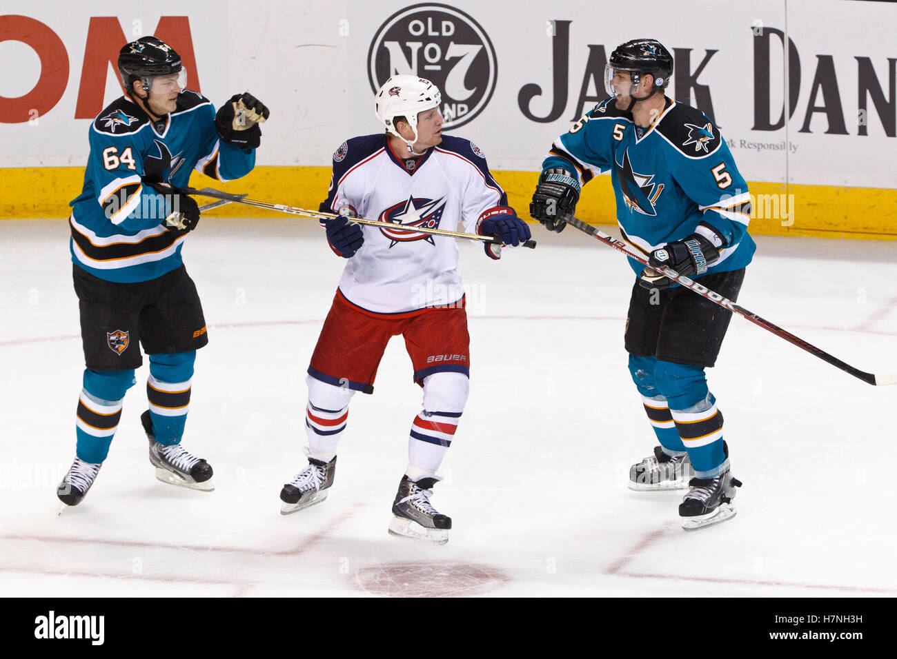 Jan 31, 2012; San Jose, CA, USA; Columbus Blue Jackets right wing Derek Dorsett (15) is confronted by San Jose Sharks left wing Jamie McGinn (64) and defenseman Colin White (5) during the third period at HP Pavilion. San Jose defeated Columbus 6-0. Stock Photo