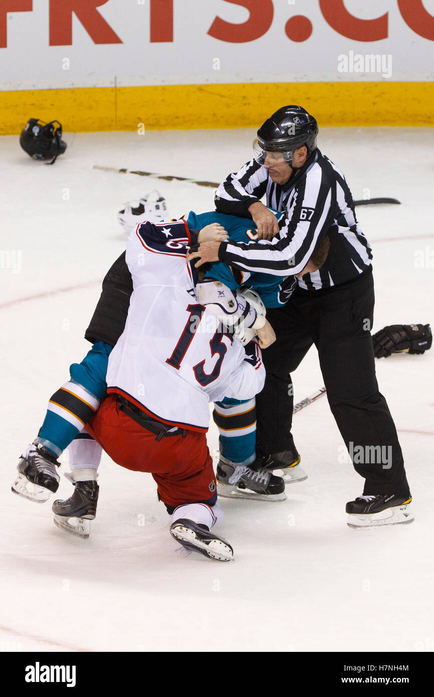 Jan 31, 2012; San Jose, CA, USA; NHL linesman Pierre Champoux (67) separates San Jose Sharks defenseman Colin White (center) and Columbus Blue Jackets right wing Derek Dorsett (15) after a fight during the third period at HP Pavilion. San Jose defeated Columbus 6-0. Stock Photo