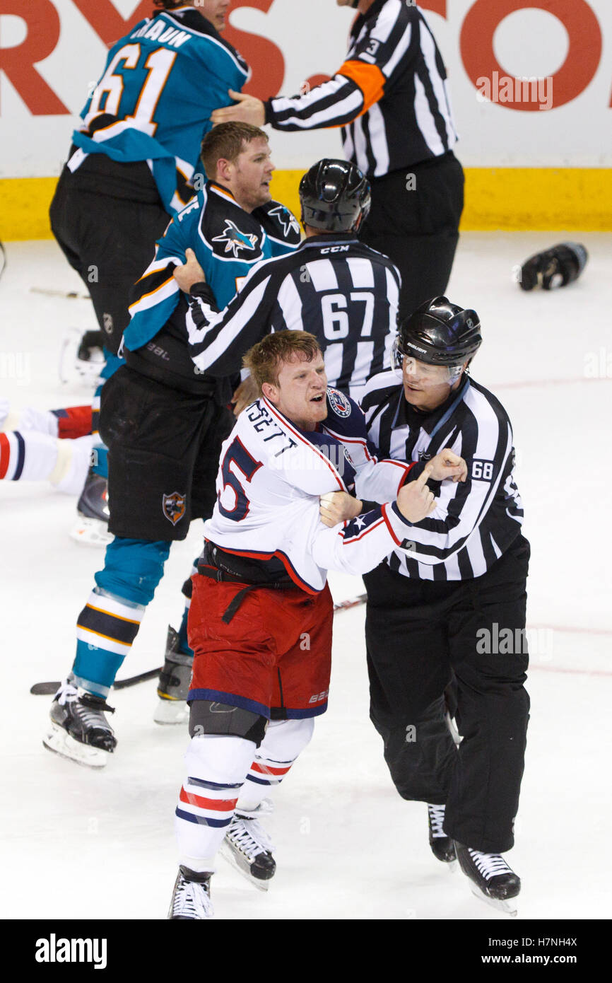 Jan 31, 2012; San Jose, CA, USA; NHL linesman Scott Driscoll (68) and linesman Pierre Champoux (67) separate Columbus Blue Jackets right wing Derek Dorsett (bottom, left) and San Jose Sharks defenseman Colin White (middle, left) after a fight during the third period at HP Pavilion. San Jose defeated Columbus 6-0. Stock Photo