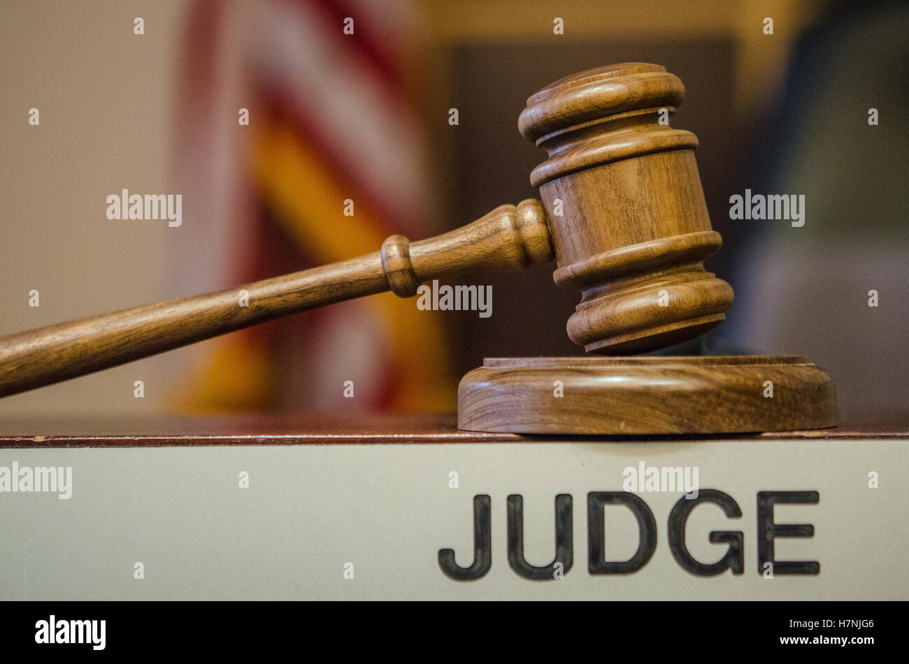 Gavel up at Judge's bench with sign, chair and flag Stock Photo