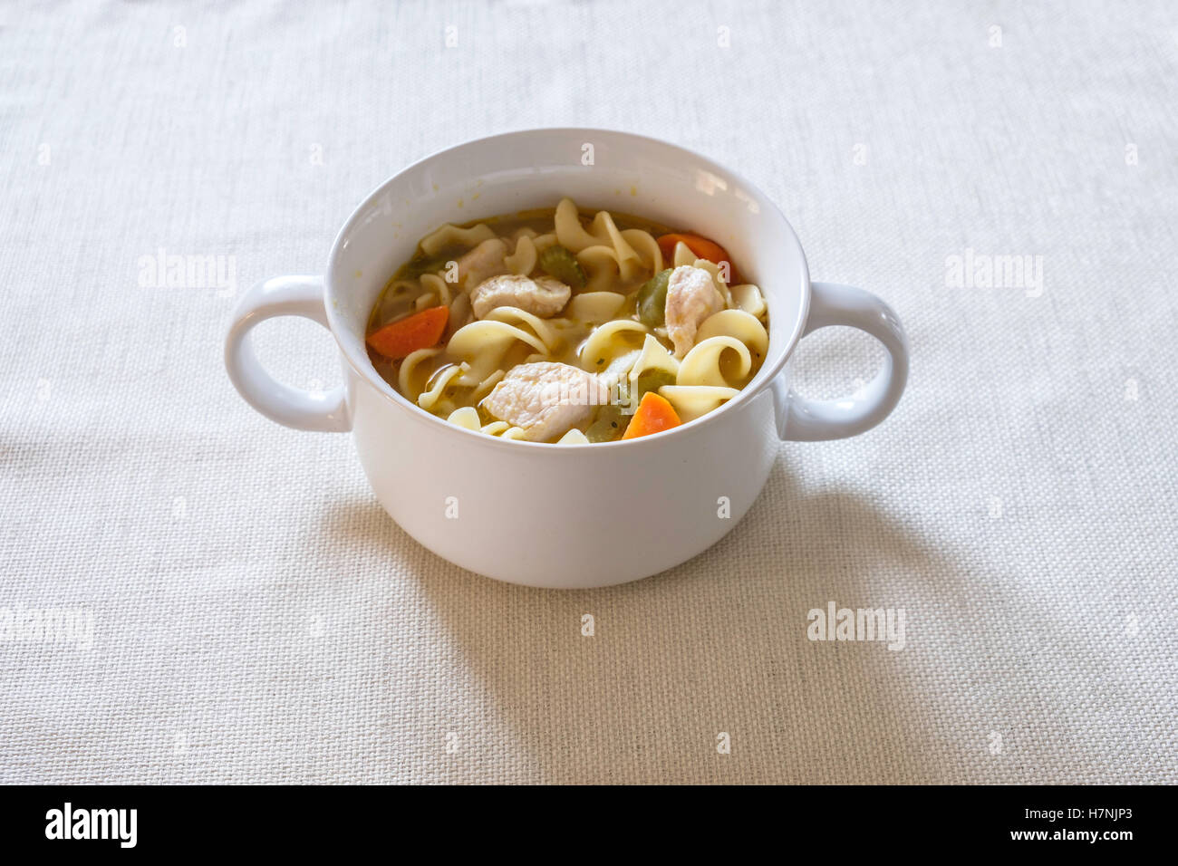 Home made chicken noodle soup, comfort food, containing carrots and celery served in a white bowl. Stock Photo