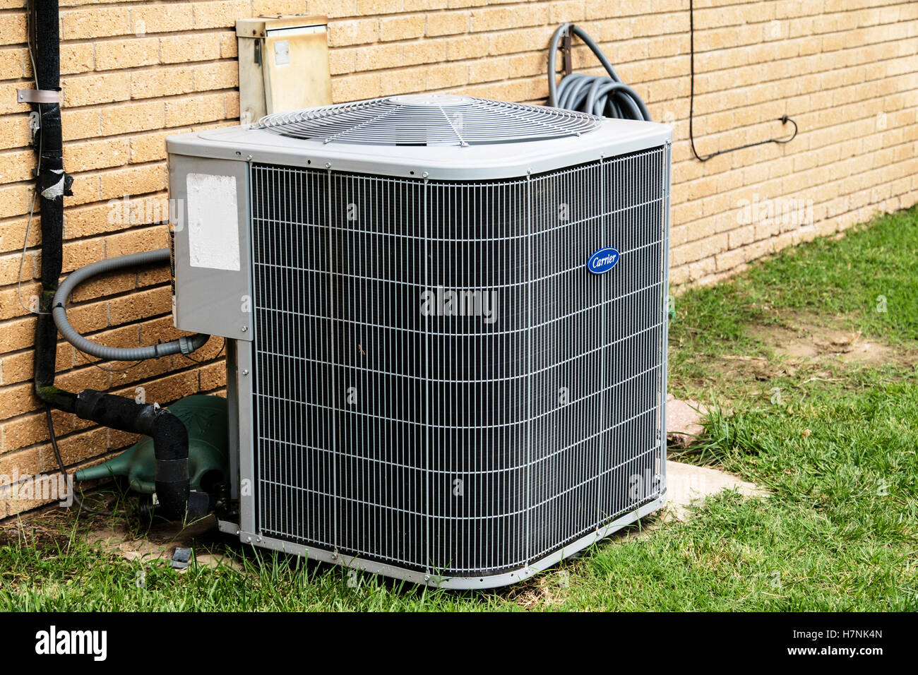 An air conditioner in the back yard of a brick home in Oklahoma City