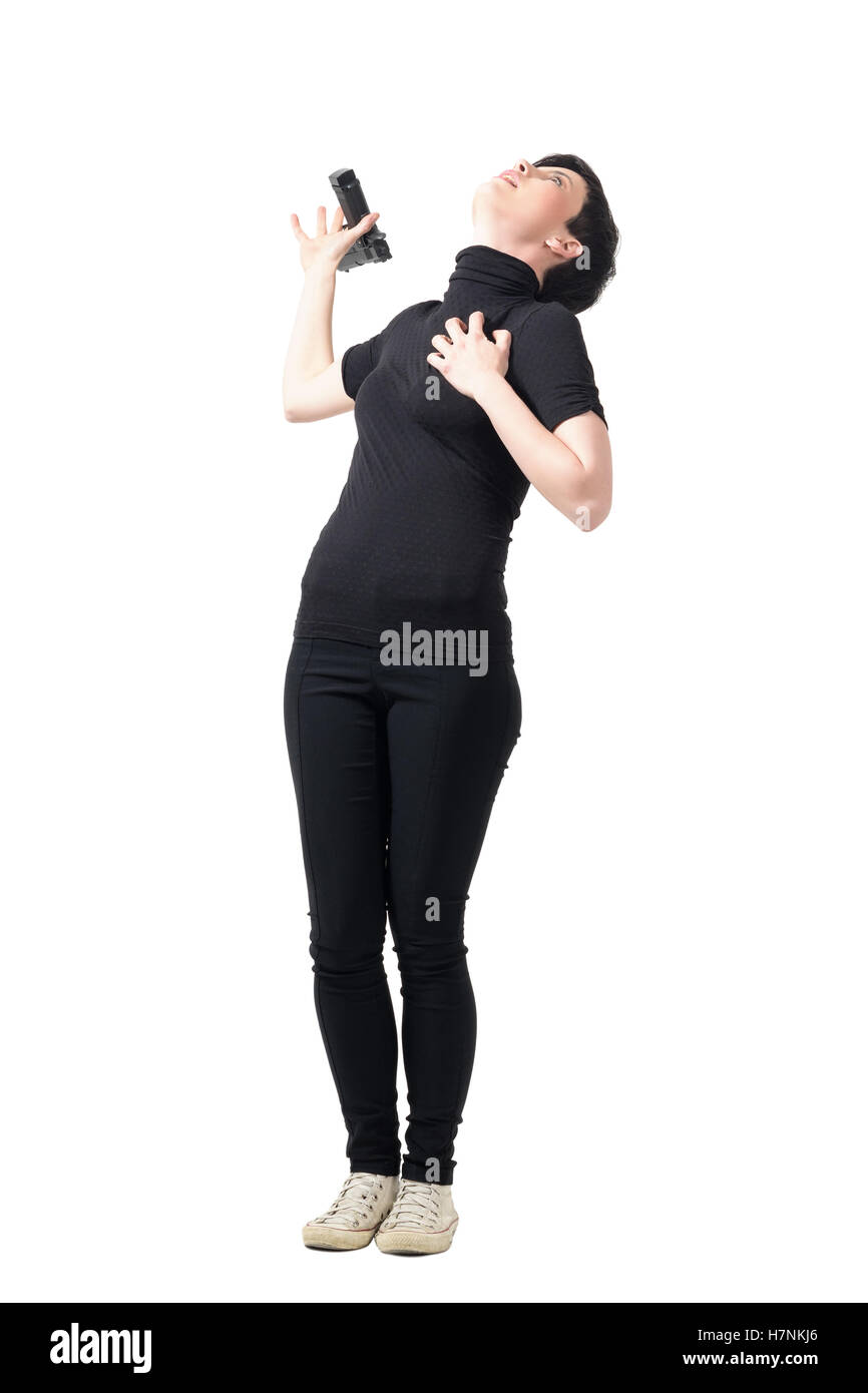 Female spy in black clothes falling backwards and dropping gun while getting shot. Full body length portrait isolated on white Stock Photo