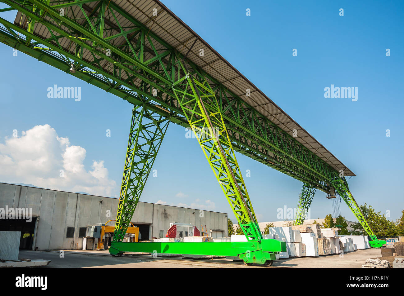 Green gantry crane at work in a warehouse of marble blocks Stock Photo