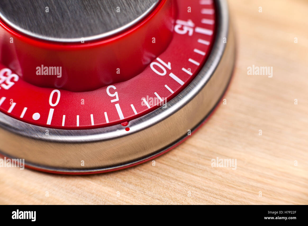 Macro view of a red kitchen egg timer showing 5 minutes on wooden background Stock Photo