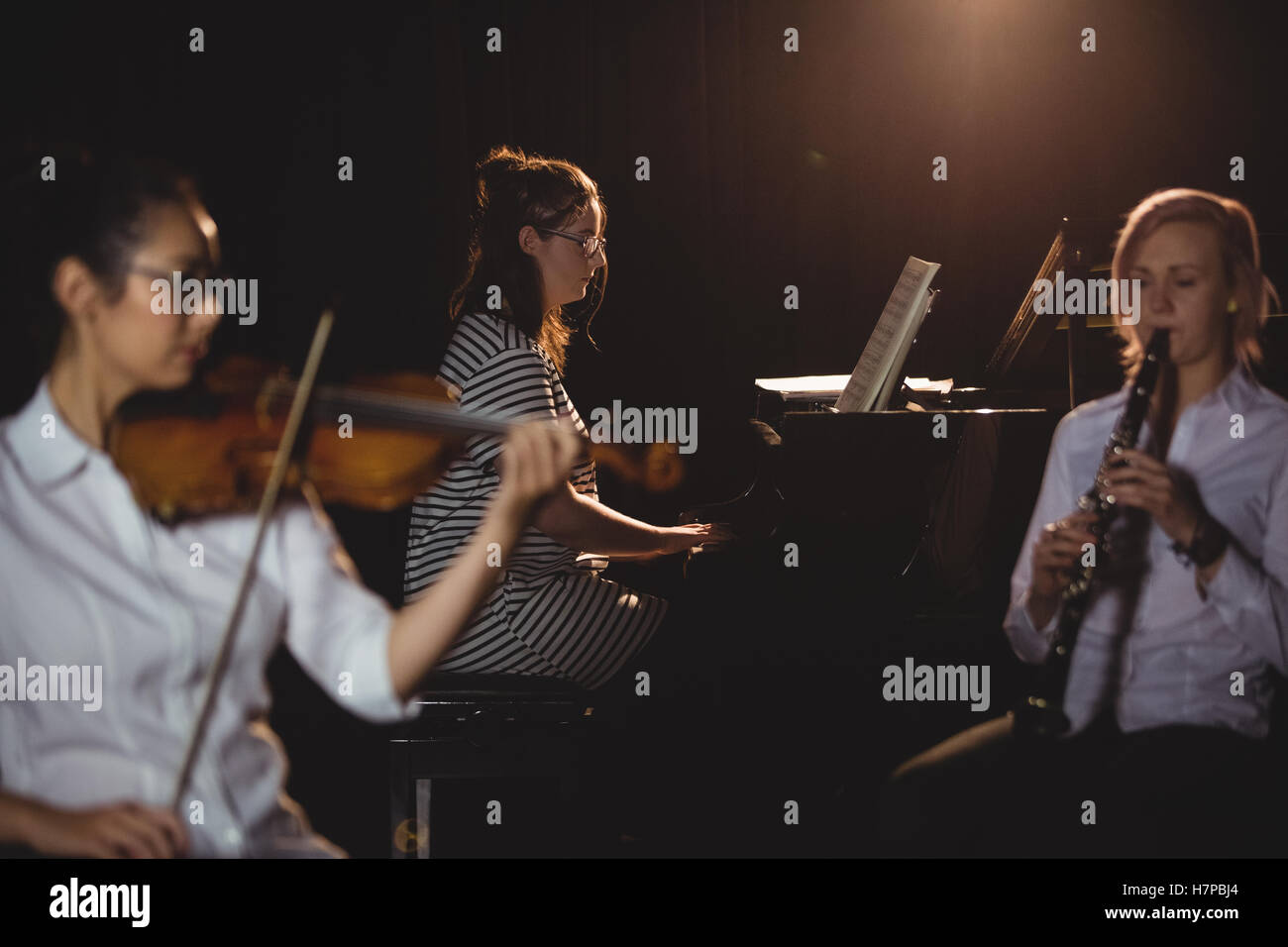 Three female students playing piano, and violin Stock Photo