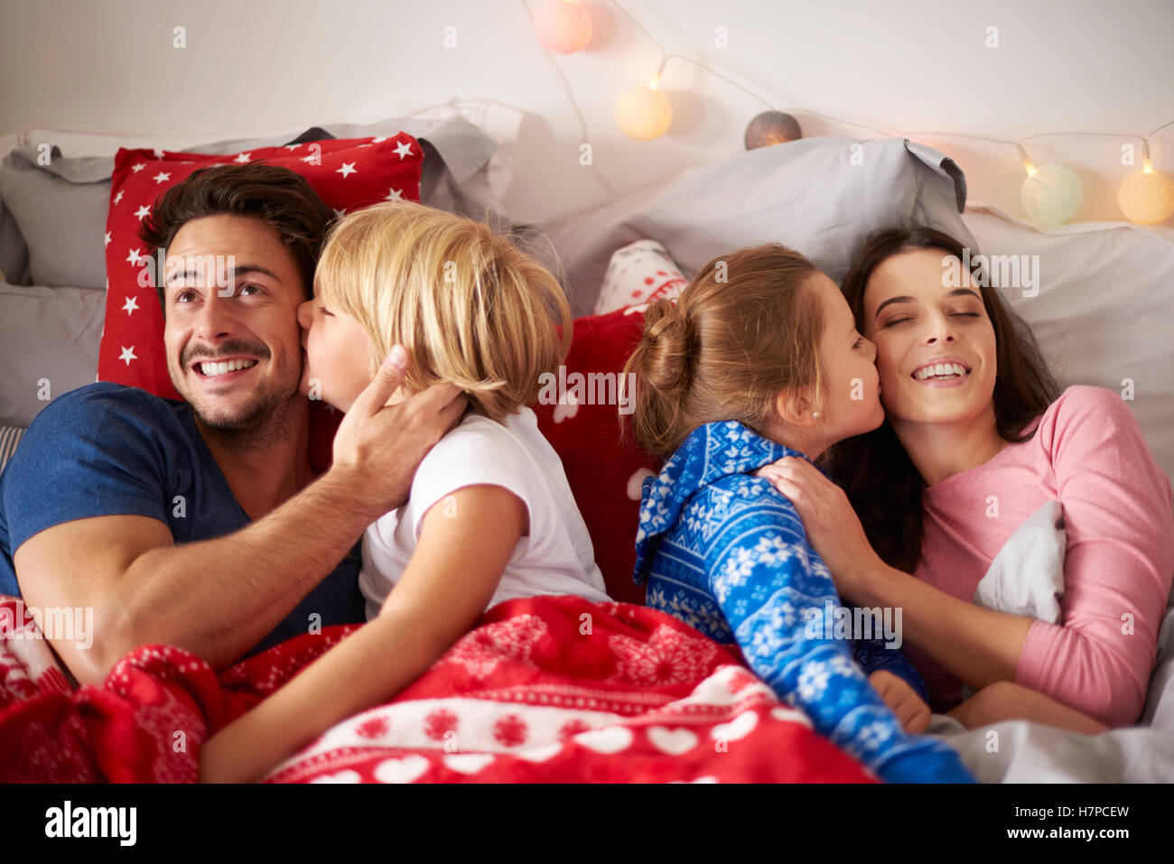 Kids kissing their parents at Christmas Stock Photo