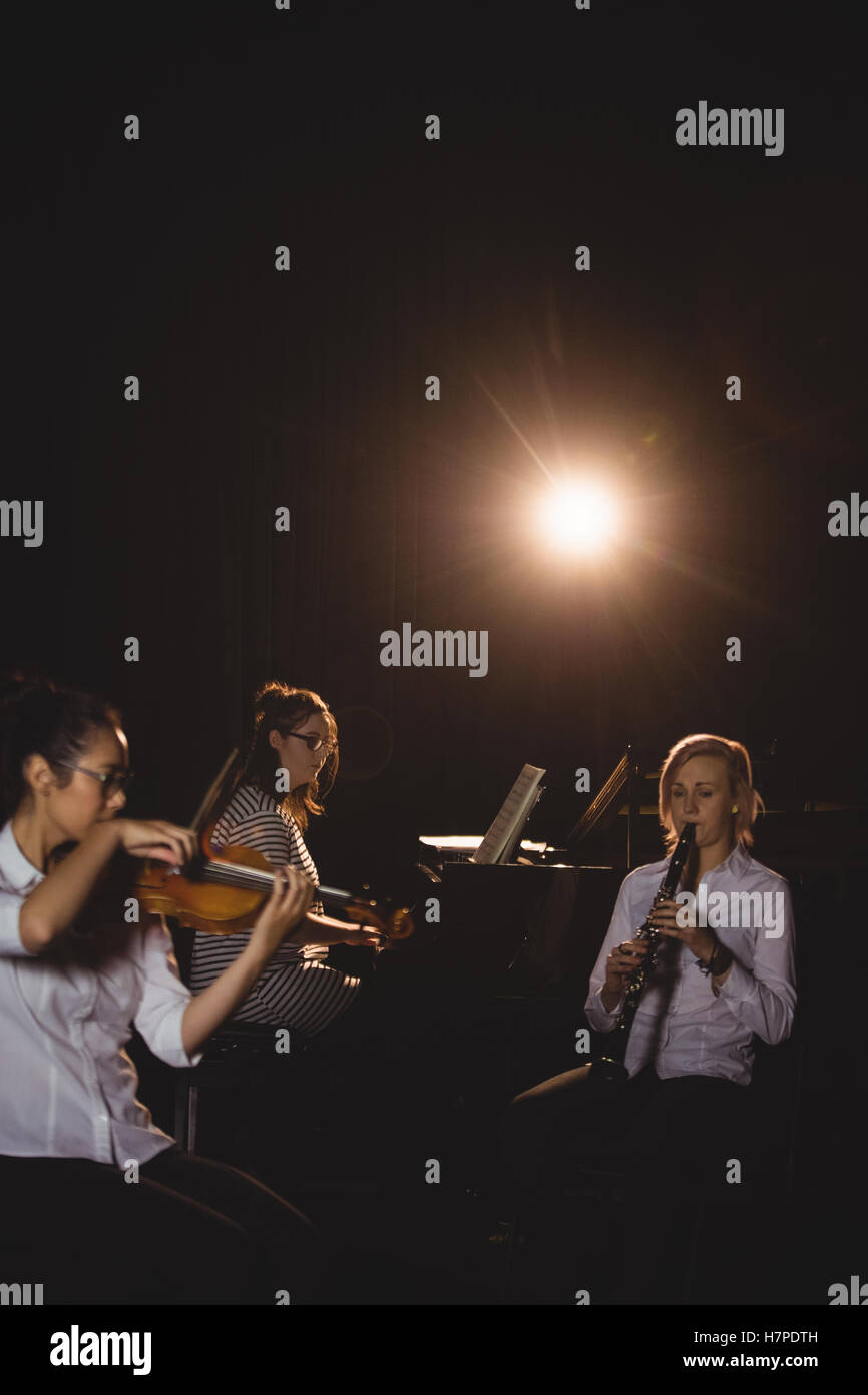 Three female students playing piano, and violin Stock Photo