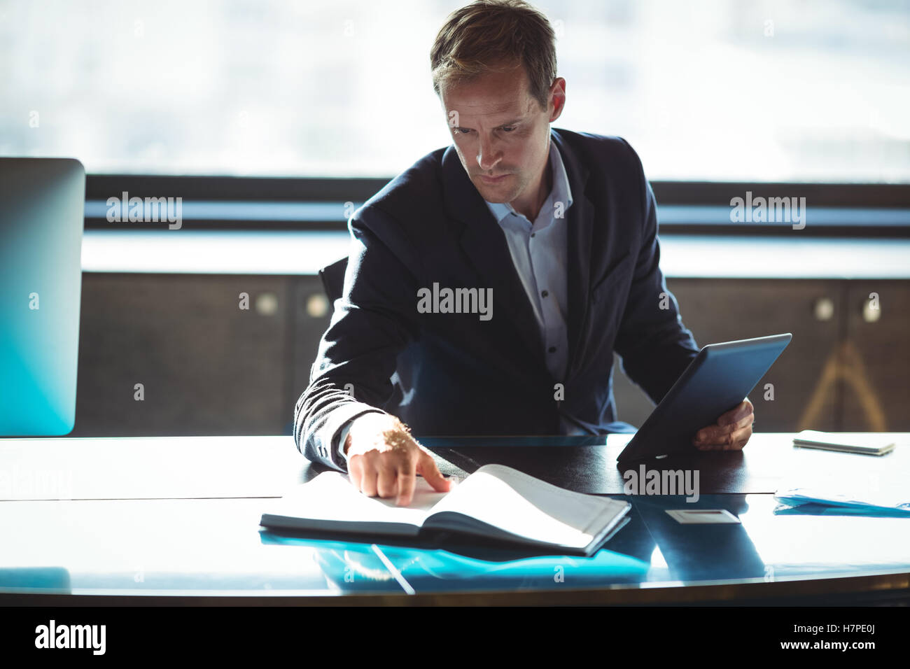 Businessman checking his diary while using digital tablet Stock Photo