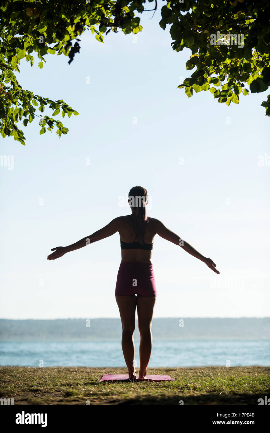 Rear view of woman performing yoga in garden Stock Photo - Alamy