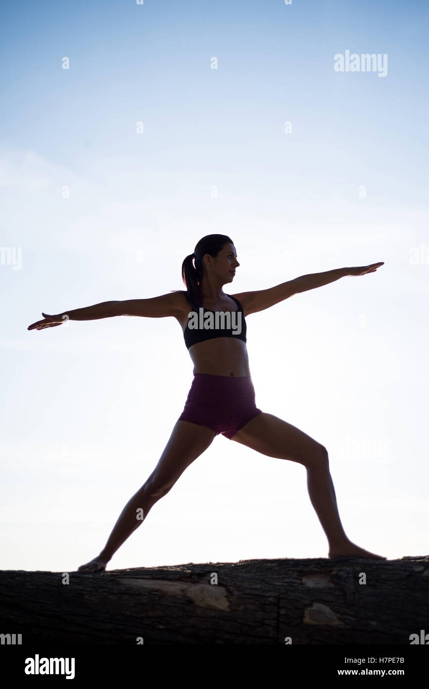 Woman performing yoga on driftwood Stock Photo Alamy