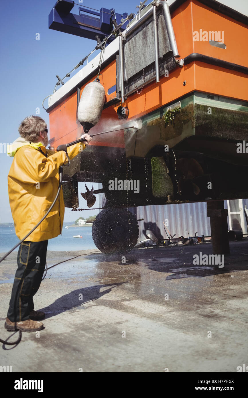 Man cleaning boat with pressure washer Stock Photo