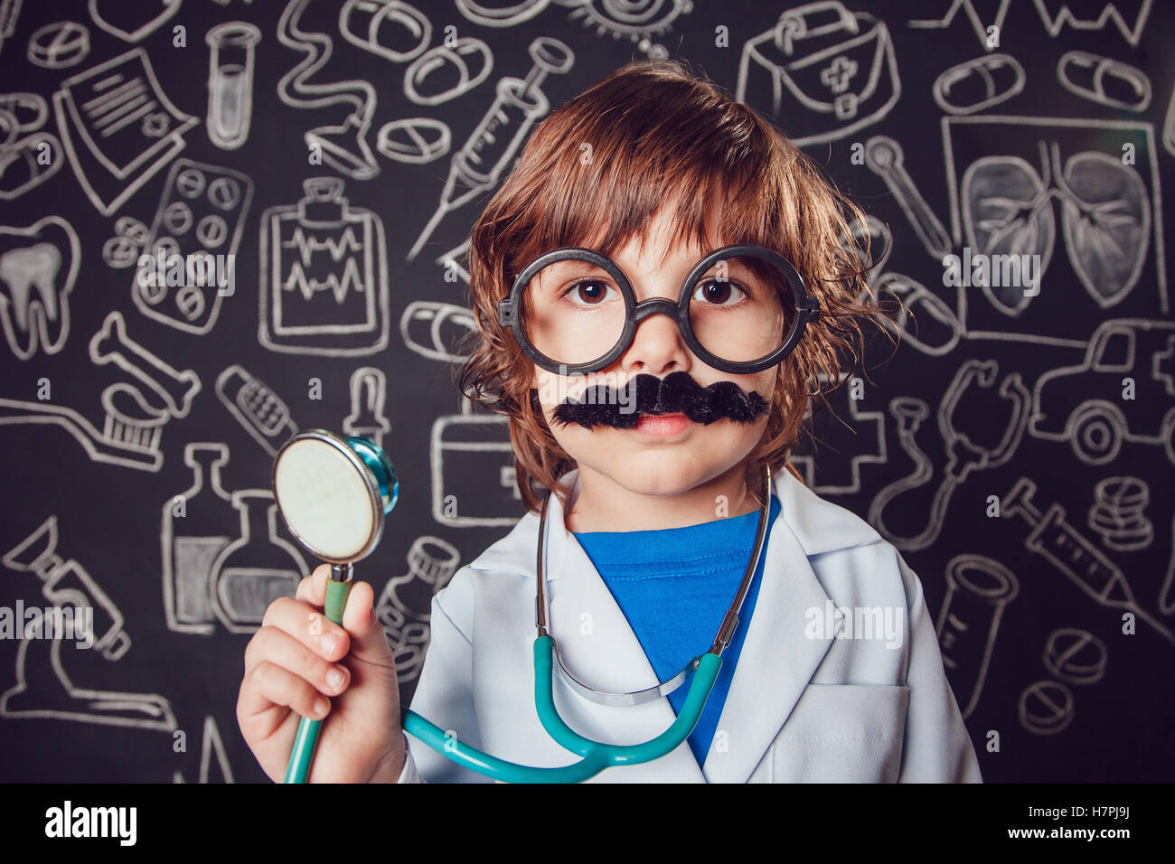 Happy little boy in doctor costume holding sthetoscope on dark