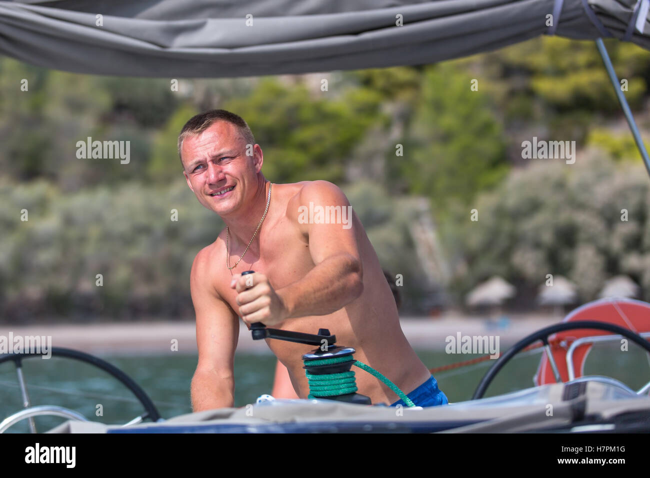 Sailing, man pulling ropes, winding sheets around winches. Luxery yacht boat. Stock Photo