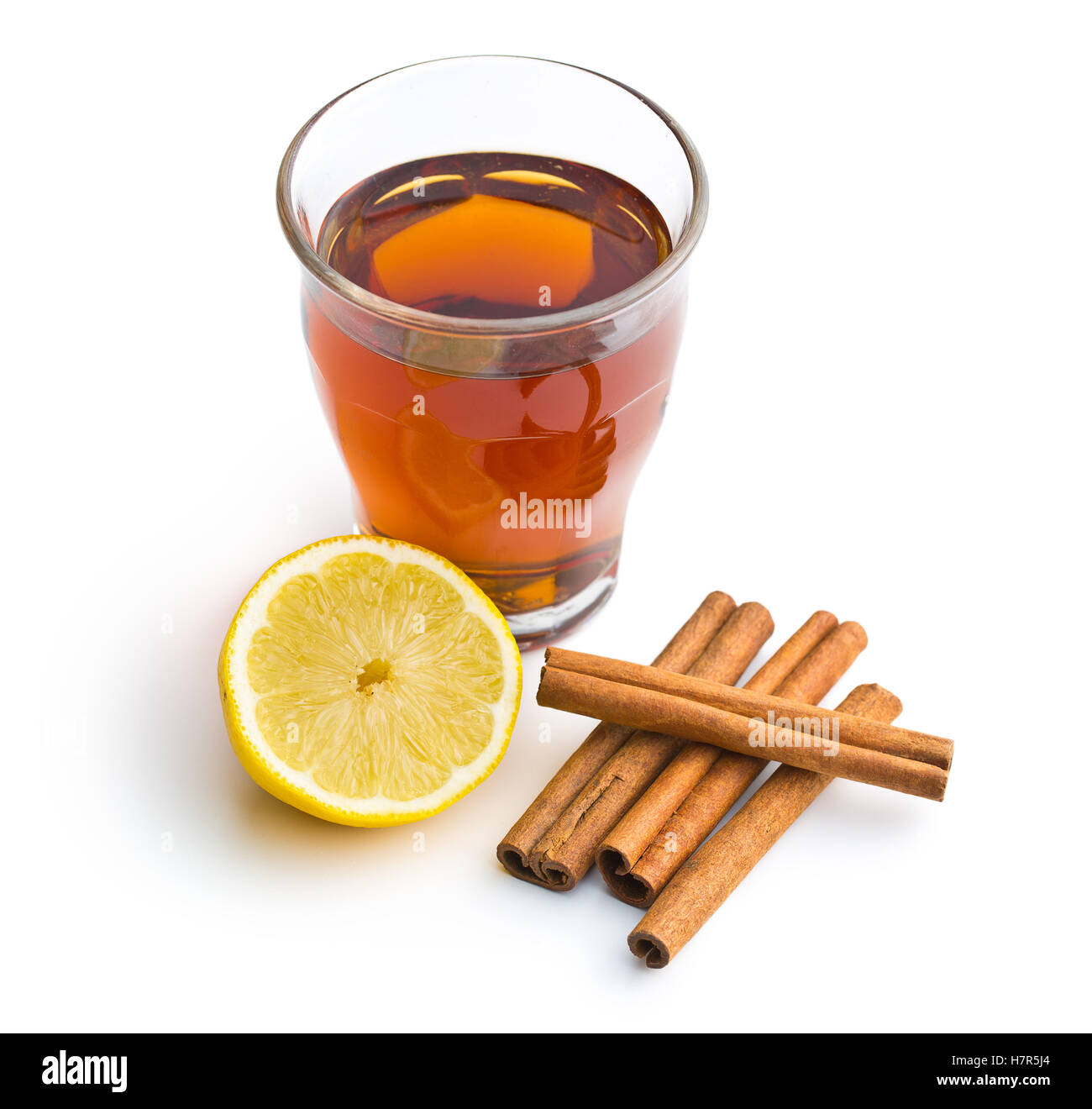 Tea in glass cup, lemon and cinnamon sticks isolated on white background. Stock Photo