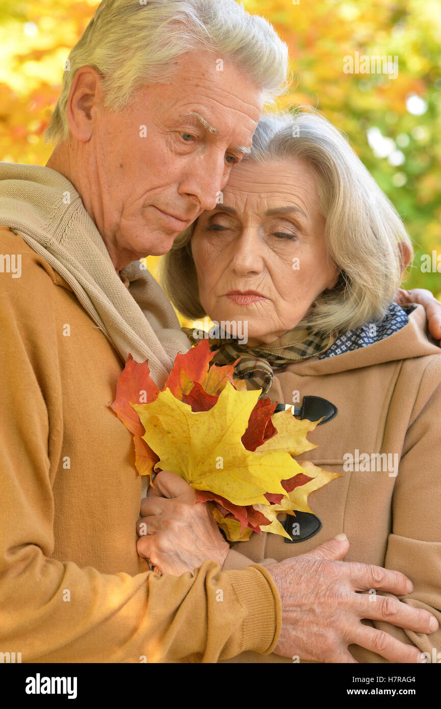 Sad elderly couple standing embracing outdoors Stock Photo