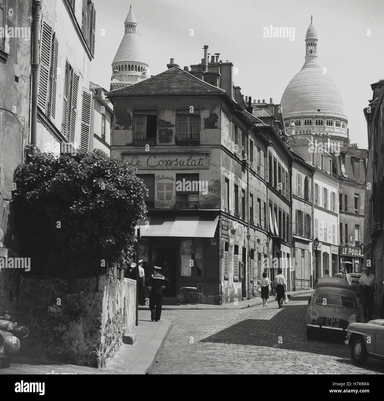 1950s, historical, a cobbled Parisian side-street, Rue Norvins in Montmartre, showing the cafe and bar, 'Le Consulat', and the domes of the Sacre-Coeur Church in the background. Stock Photo