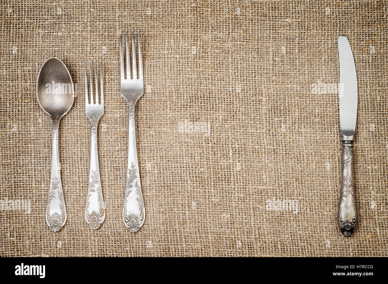 Rustic jute background with vintage silver fork spoon and knife. Stock Photo