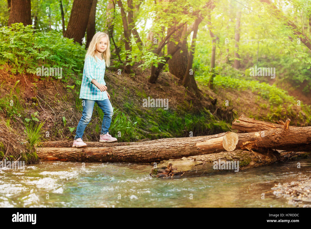 Little girl crossing log bridge in the forest Stock Photo - Alamy